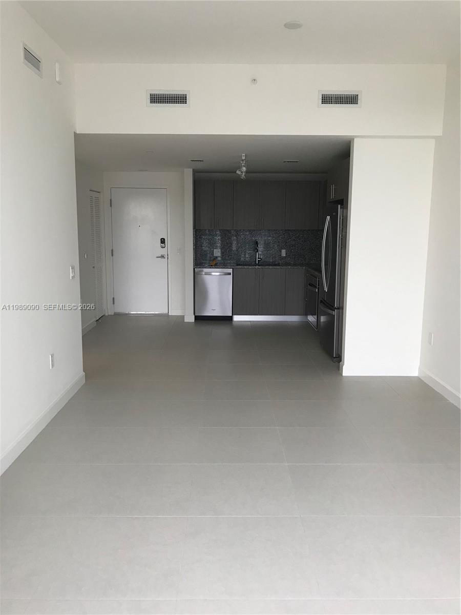 A modern kitchen with gray cabinetry and stainless steel appliances opens into a tiled living area — 5350 NW 84th Ave # 1814, Doral FL 33166, DORAL, FL