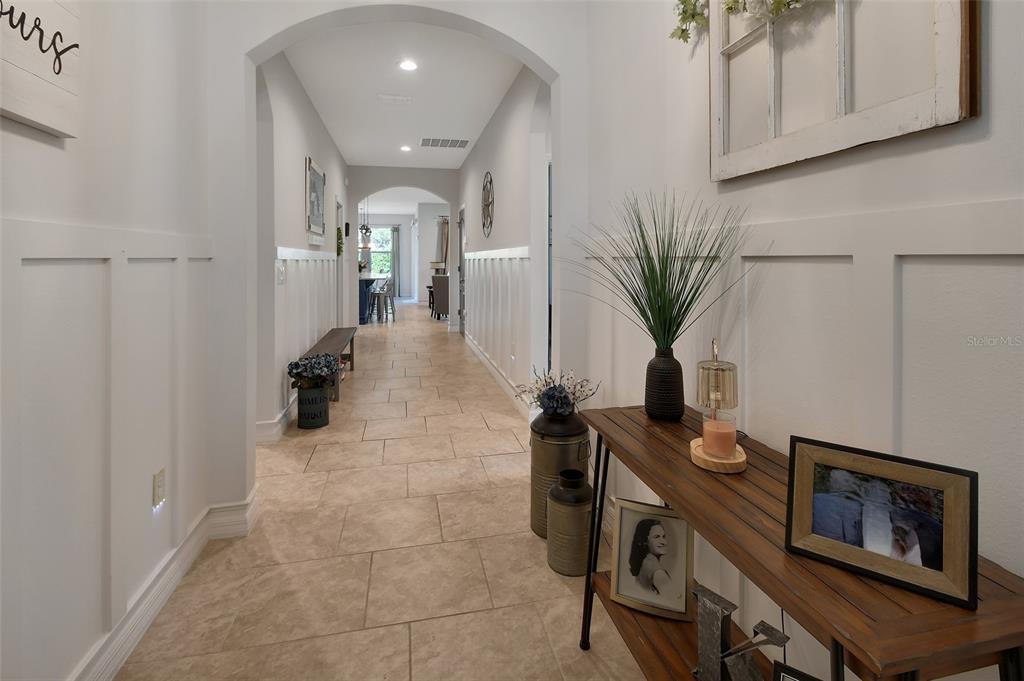 A long hallway with tile flooring, white wainscoting, and an arched entryway — 744 E VICTORIA TRAILS BOULEVARD, DELAND, FL