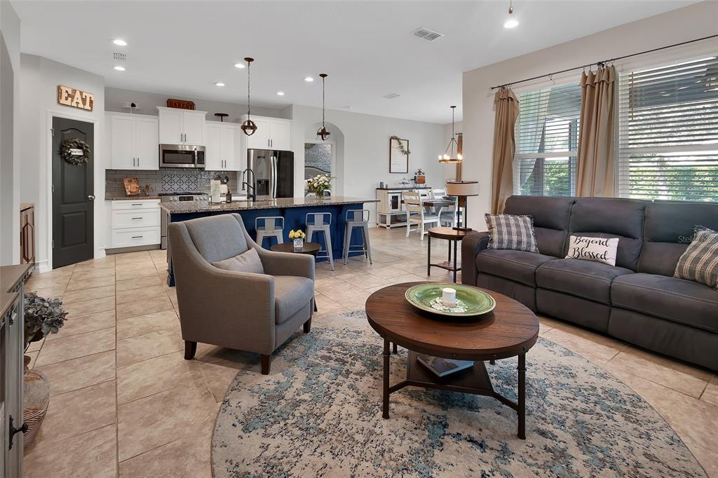 An open-concept kitchen and living area features a blue island, gray sofa, and tile flooring — 744 E VICTORIA TRAILS BOULEVARD, DELAND, FL