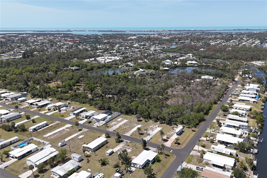 An aerial view shows a residential neighborhood with mobile homes near a body of water — 1256 IBIS DRIVE, ENGLEWOOD, FL