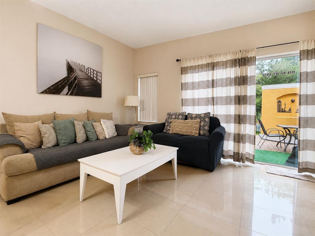 A living room features a tan sofa, a dark loveseat, and a sliding door to a patio — 4715 FLAGLER BEACH WAY, KISSIMMEE, FL