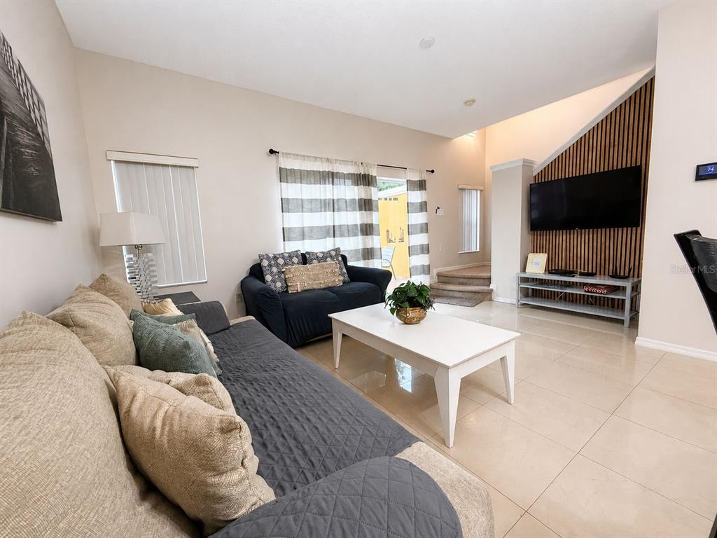 A living room features a large sectional sofa, a coffee table, and a wall-mounted television — 4715 FLAGLER BEACH WAY, KISSIMMEE, FL