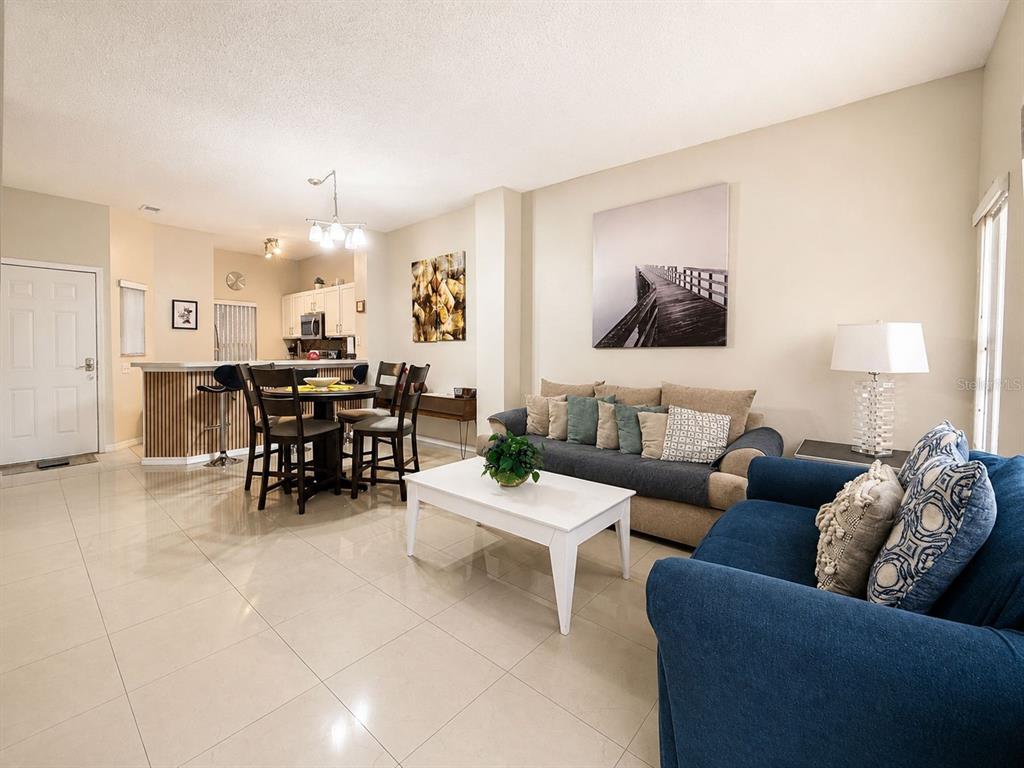 An open-concept living and dining area features tile flooring, a kitchen island, and neutral walls — 4715 FLAGLER BEACH WAY, KISSIMMEE, FL