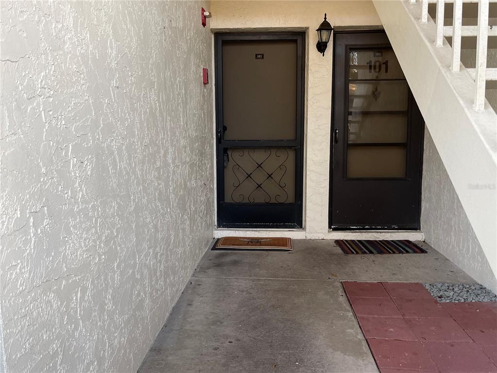 Two apartment entry doors with screen doors are located under an outdoor staircase — 103 PALMETTO COURT UNIT 103, OLDSMAR, FL