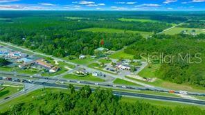 An aerial view shows a commercial property with parking lots situated near a highway and forest — 1415 NW 23RD AVENUE, CHIEFLAND, FL