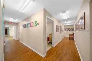 A hallway in a pediatric office features wood-look flooring and colorful lettering on the wall — 1415 NW 23RD AVENUE, CHIEFLAND, FL