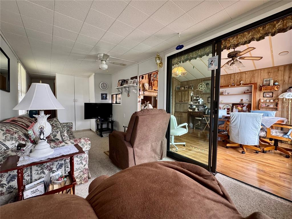 A living room with a floral sofa and brown recliner opens to a dining area — 35224 DODIE DRIVE Lot 12, ZEPHYRHILLS, FL