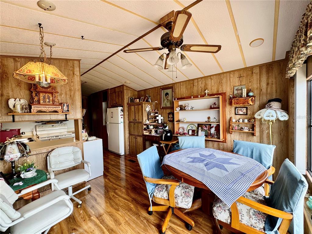 A dining area with wood-paneled walls, a ceiling fan, and a table with chairs — 35224 DODIE DRIVE Lot 12, ZEPHYRHILLS, FL
