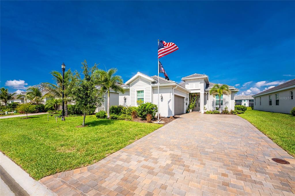 A single-story house with a paved driveway, a front lawn, and an American flag — 14840 REDBUD LANE, PUNTA GORDA, FL