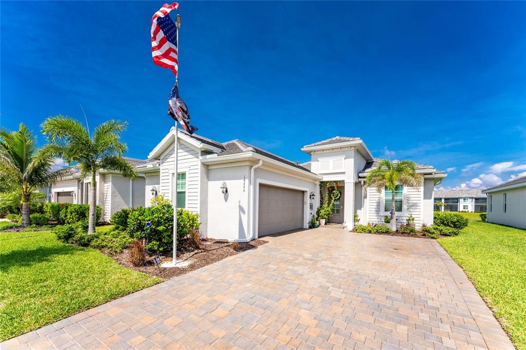 A single-story house with a paved driveway, a two-car garage, and a tall flagpole — 14840 REDBUD LANE, PUNTA GORDA, FL