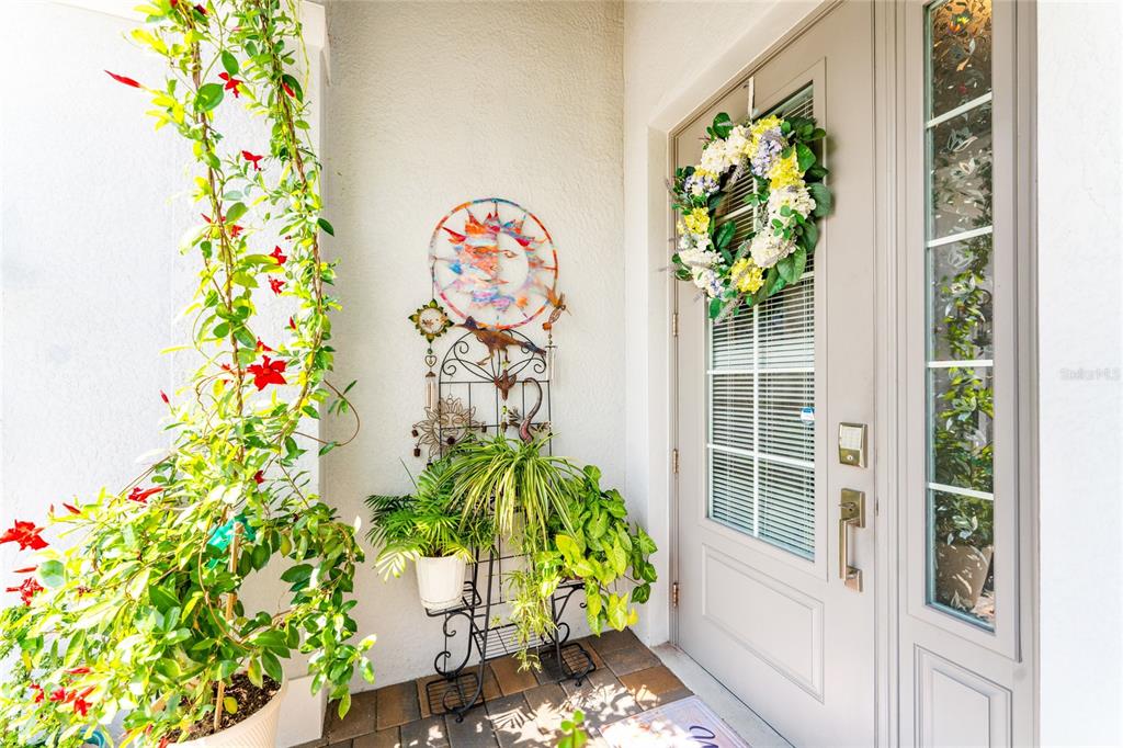 A front entryway features a light-colored door with a wreath, potted plants, and wall decor — 14840 REDBUD LANE, PUNTA GORDA, FL