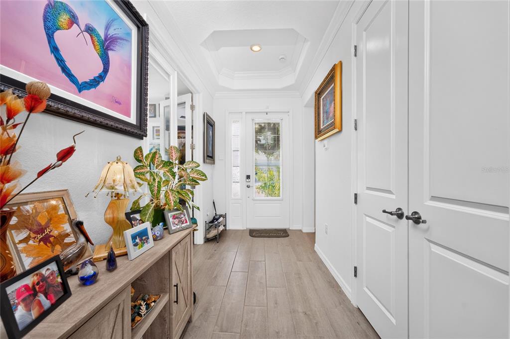 A bright entryway features wood-look tile flooring, a tray ceiling, and a white front door — 14840 REDBUD LANE, PUNTA GORDA, FL