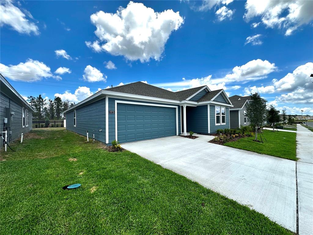 A blue-sided single-story house with a two-car garage and a concrete driveway — 1975 WILDER WAY, EAGLE LAKE, FL