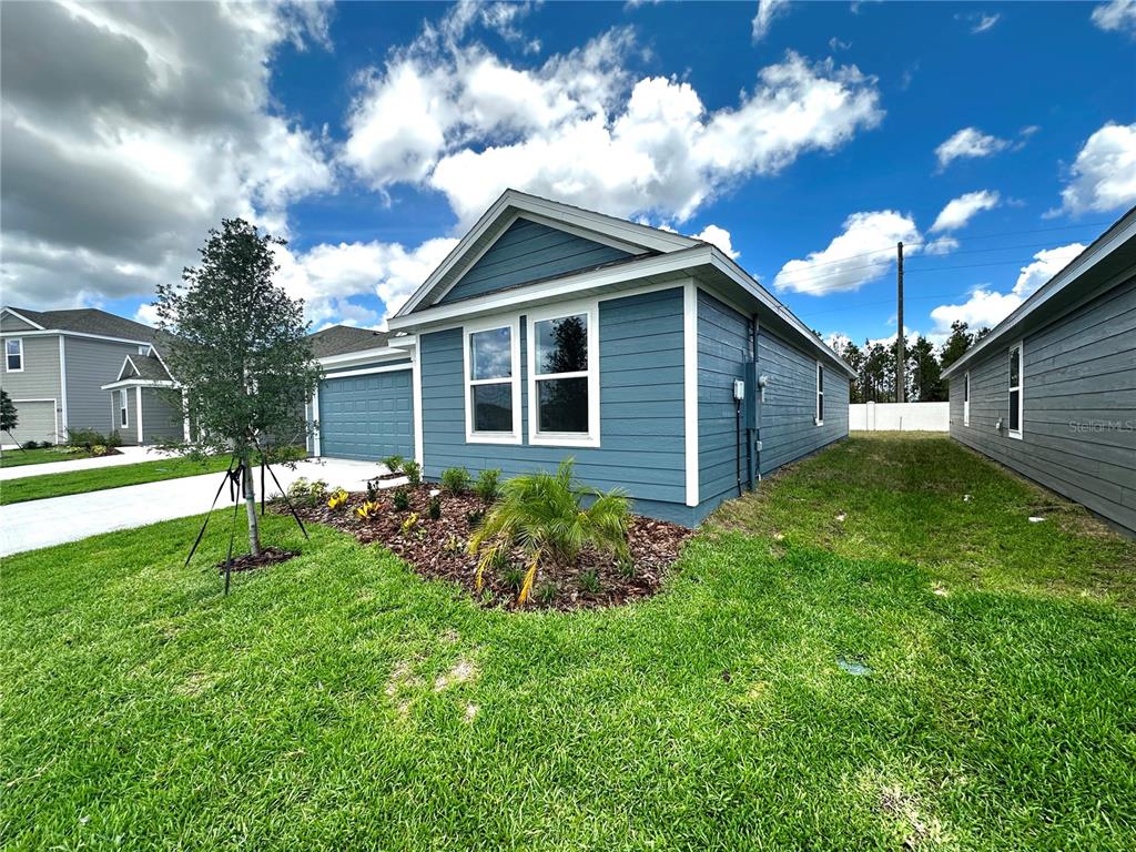 A blue single-story house with a two-car garage and a landscaped front yard — 1975 WILDER WAY, EAGLE LAKE, FL