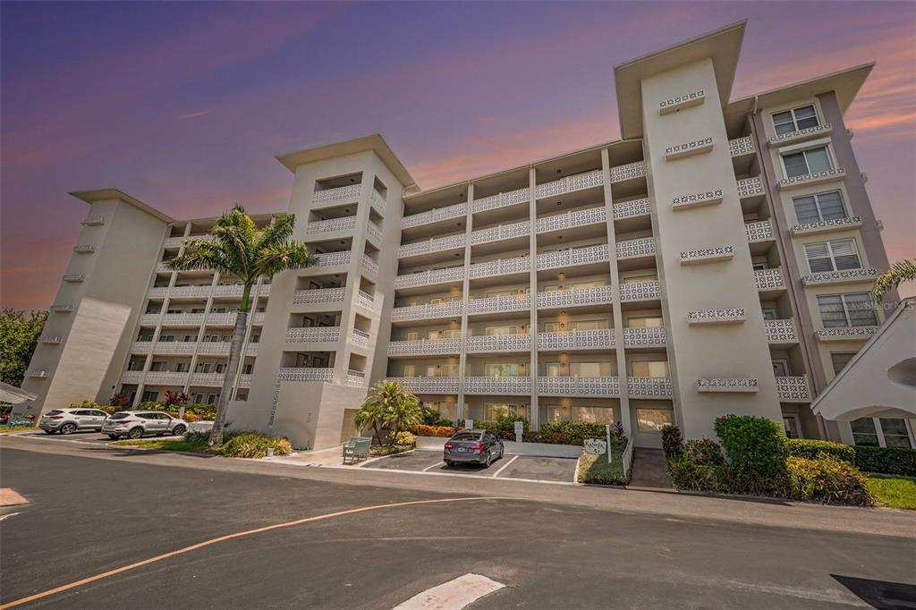 A multi-story apartment building with balconies and a parking lot in front — 1235 S HIGHLAND AVENUE UNIT 5-703, CLEARWATER, FL