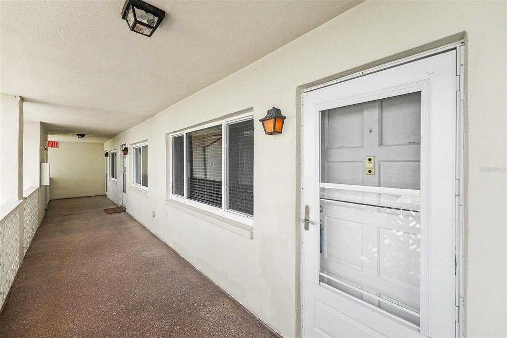 An exterior walkway features a white door with a screen and a large window — 1235 S HIGHLAND AVENUE UNIT 5-703, CLEARWATER, FL