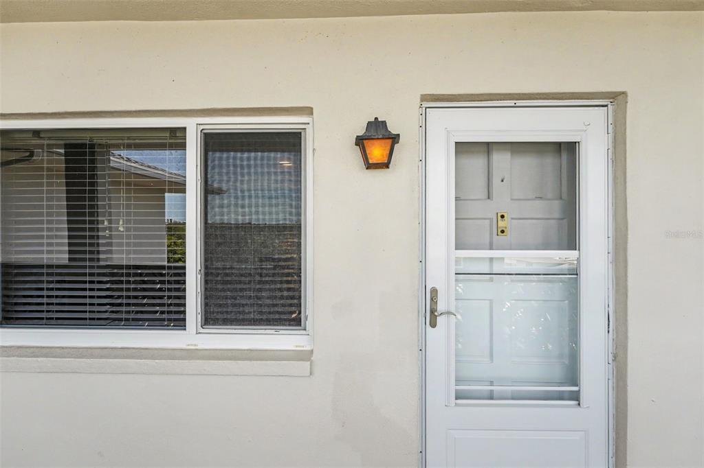 An exterior view showing a window with blinds, a wall-mounted light fixture, and a door — 1235 S HIGHLAND AVENUE UNIT 5-703, CLEARWATER, FL