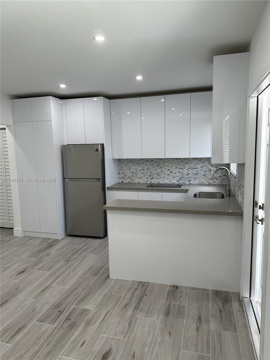 A modern kitchen features white cabinets, stainless steel appliances, and gray tile flooring — 551 SW 57th Ave # 2, Miami FL 33144, MIAMI, FL
