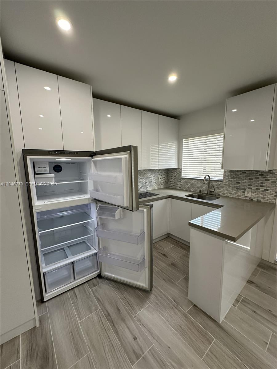 A modern kitchen features white glossy cabinets, gray countertops, and a stainless steel refrigerator — 551 SW 57th Ave # 2, Miami FL 33144, MIAMI, FL