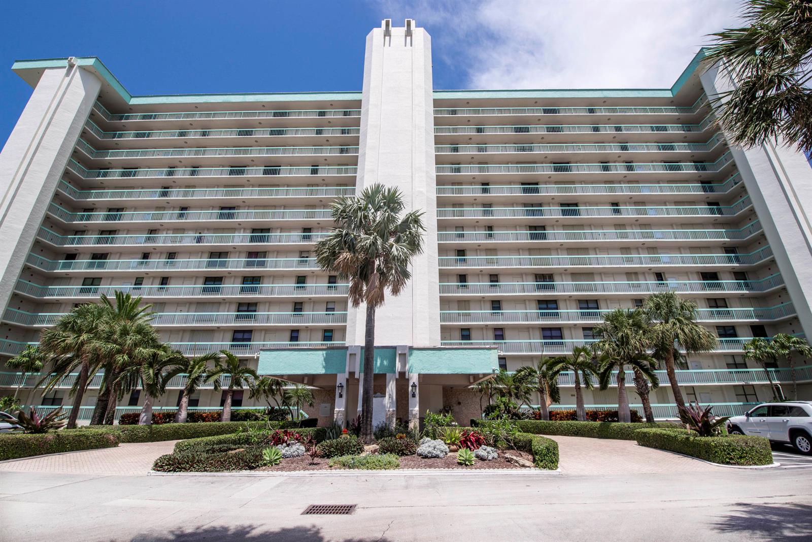 A multi-story white apartment building with teal balconies and palm trees in the foreground — 9940 S Ocean Drive # G5, Jensen Beach FL 34957, JENSEN BEACH, FL