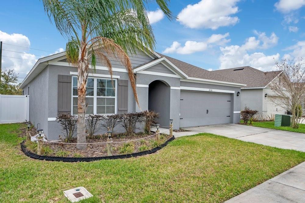 A gray single-story house with a two-car garage, a palm tree, and a front lawn — 2636 NEVERLAND DRIVE, NEW SMYRNA BEACH, FL