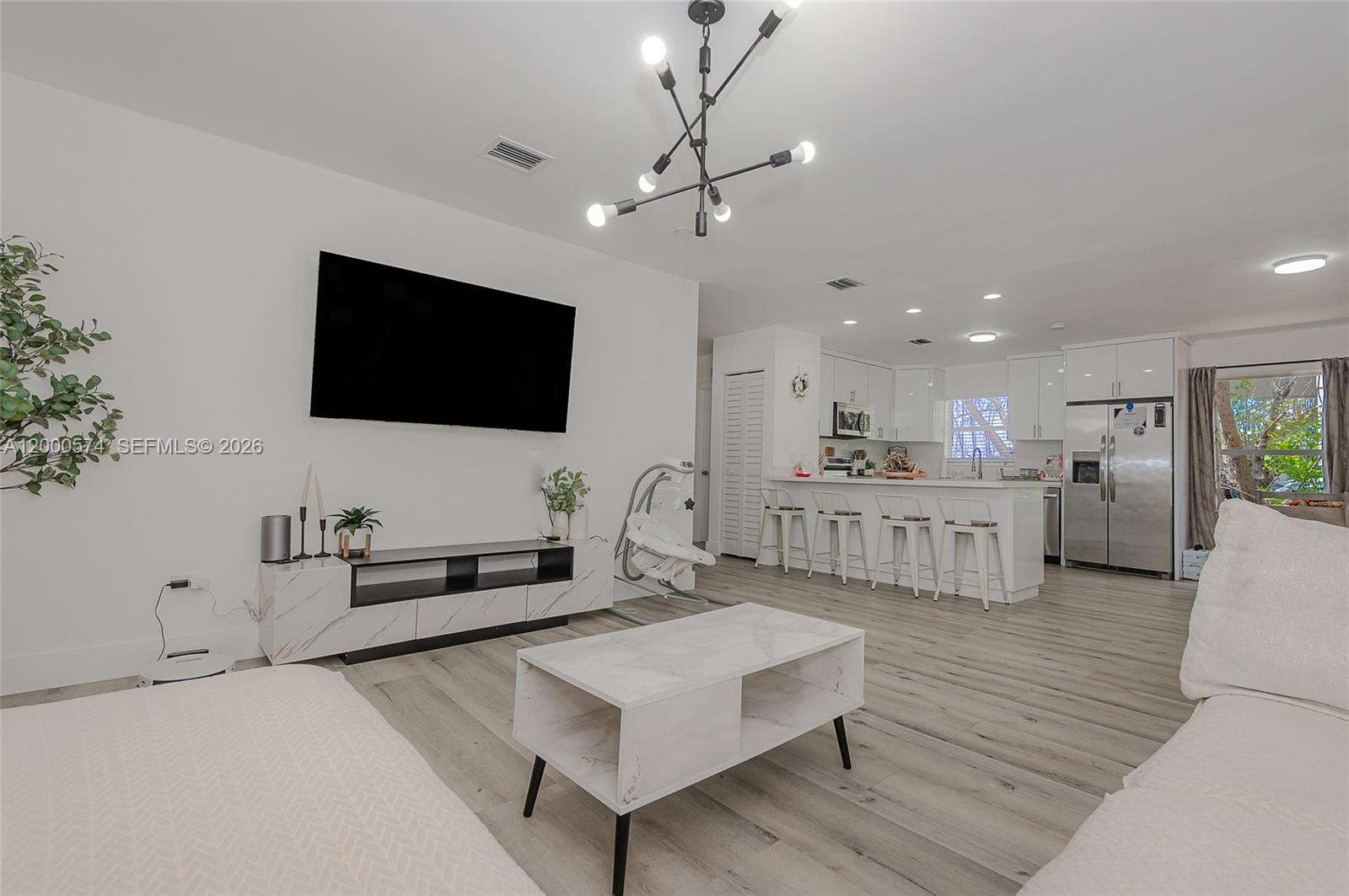 A modern open-concept living room features light wood flooring, a marble-topped coffee table, and kitchen — 367 Buttonwood Shores Dr, Key Largo FL 33037, KEY LARGO, FL
