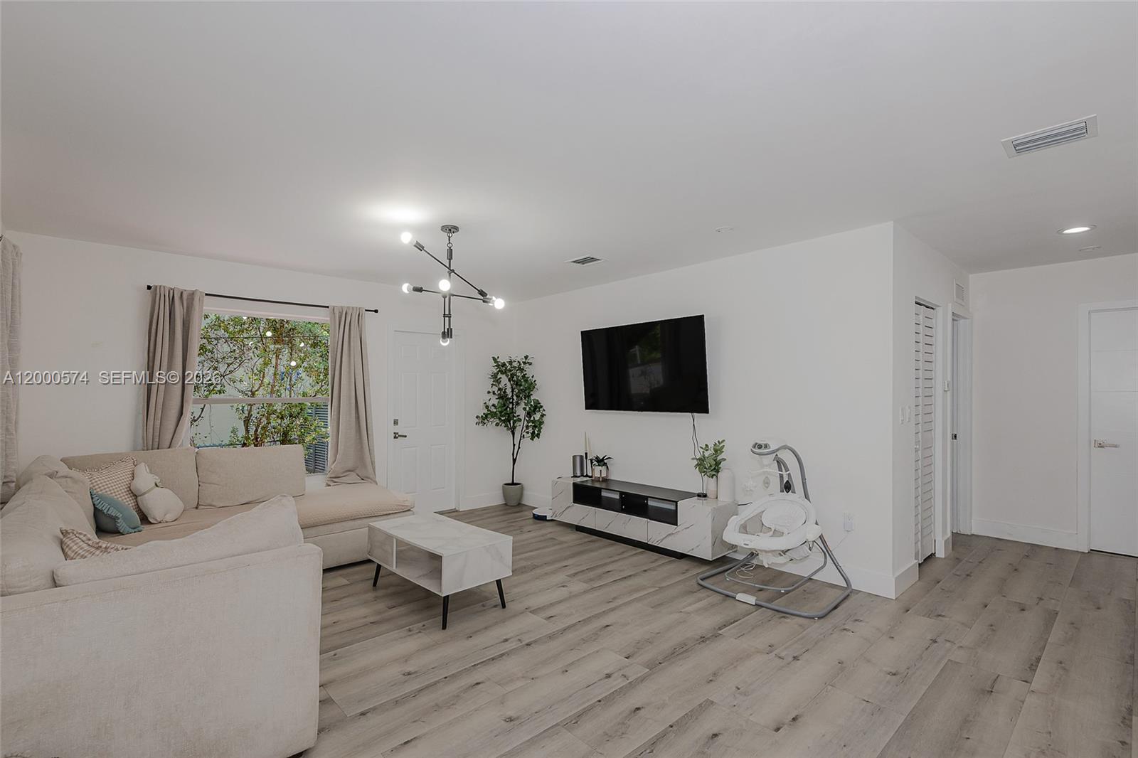 A living room features light wood-look flooring, a sectional sofa, and a wall-mounted television — 367 Buttonwood Shores Dr, Key Largo FL 33037, KEY LARGO, FL