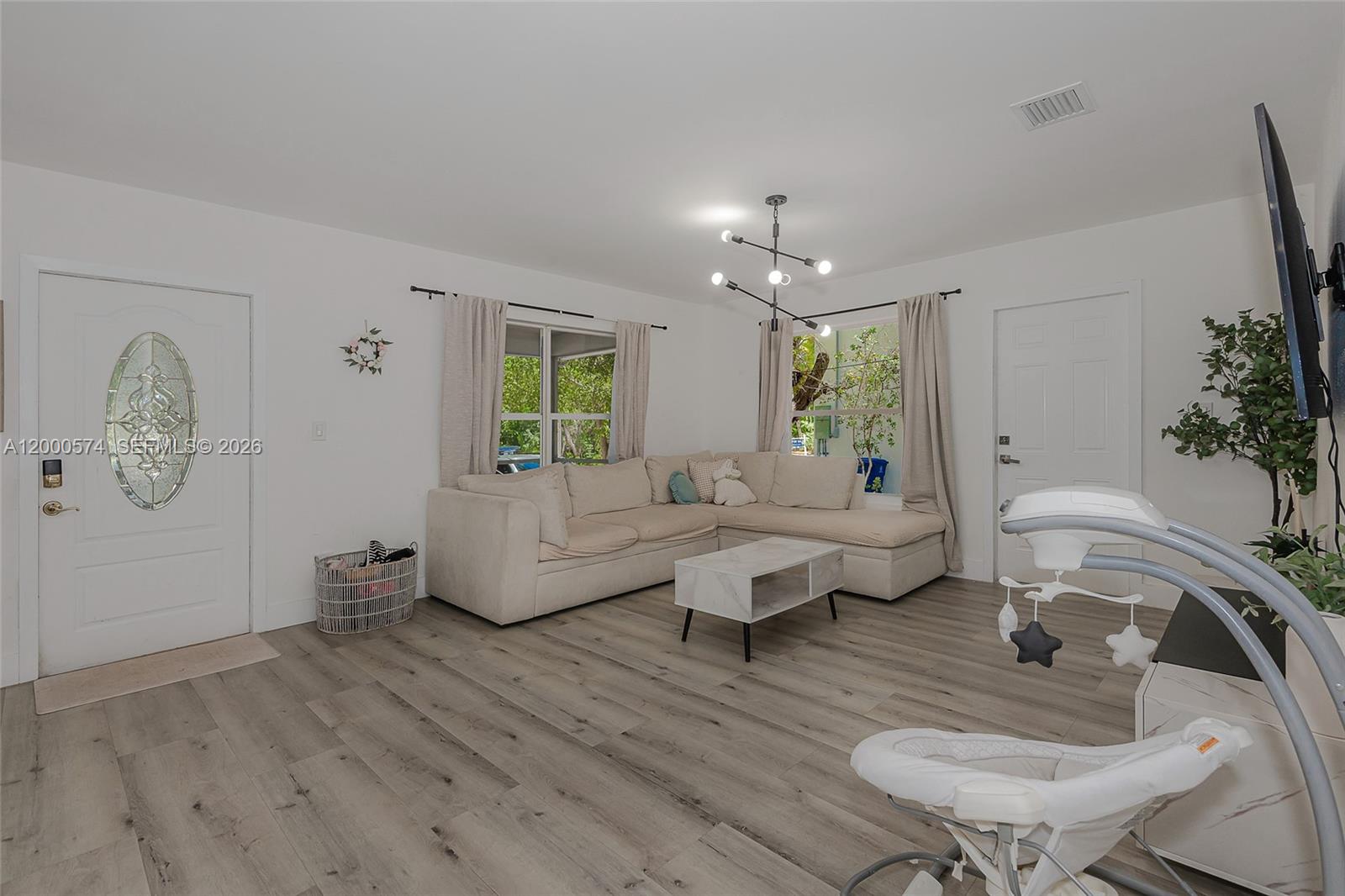 A living room features light wood-look flooring, a beige sectional sofa, and a modern chandelier — 367 Buttonwood Shores Dr, Key Largo FL 33037, KEY LARGO, FL