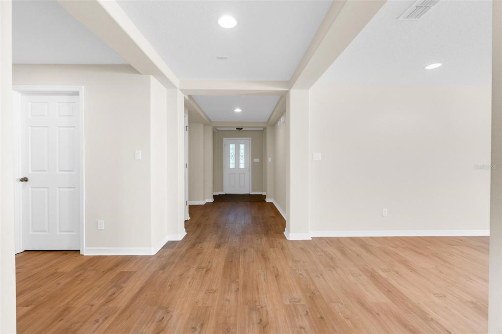A view of a home entryway with wood-look flooring, white walls, and a front door — 2613 BREEZY MEADOW ROAD, APOPKA, FL