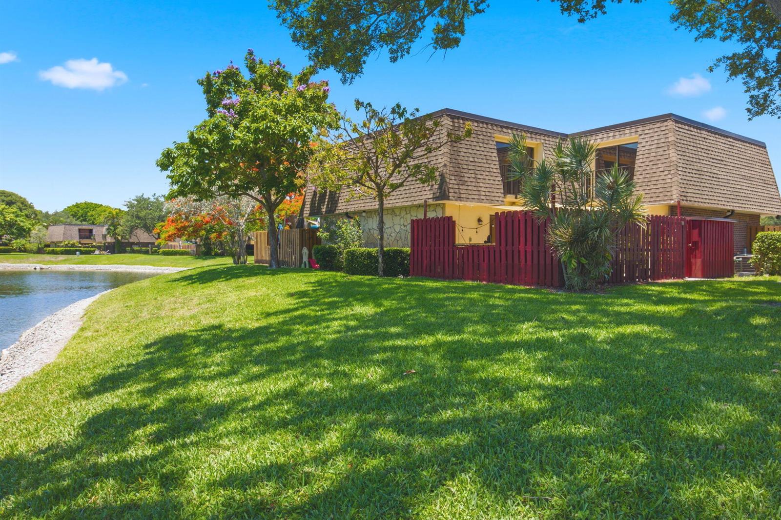 A two-story building with a brown mansard roof sits beside a lake and lawn — 2883 SW 22nd Circle # 51a, Delray Beach FL 33445, DELRAY BEACH, FL