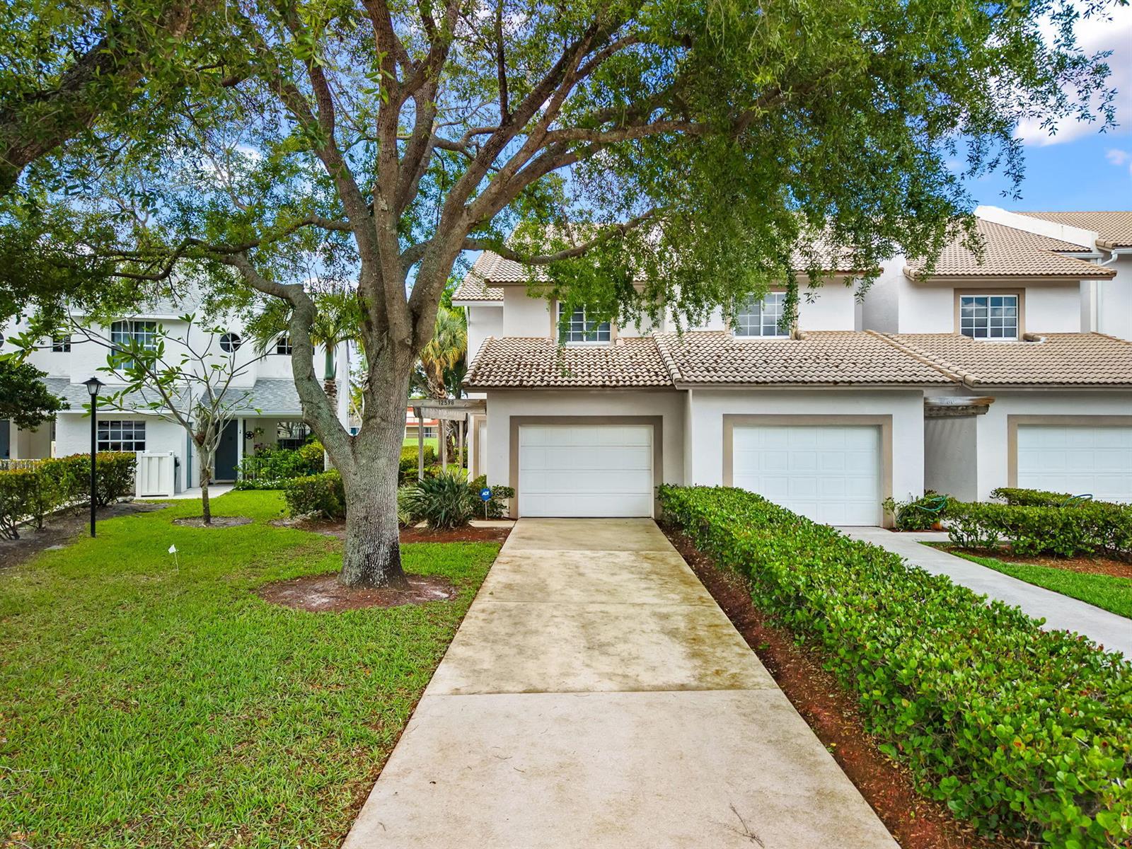A two-story townhouse with a white stucco exterior, a tile roof, and a concrete driveway — 12598 Westhampton Circle, Wellington FL 33414, WELLINGTON, FL