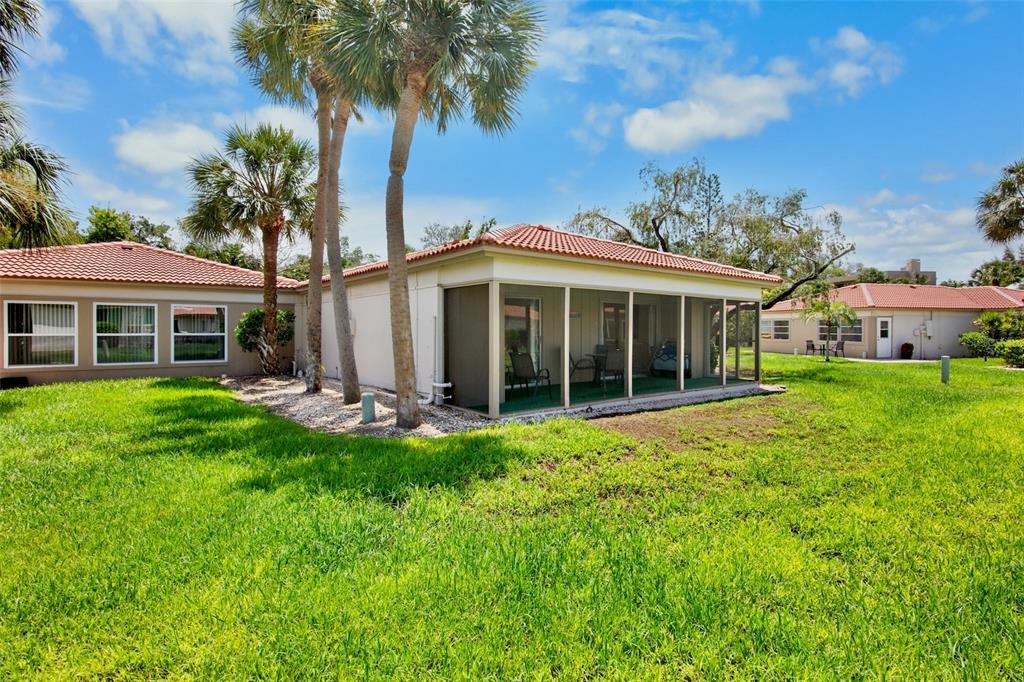 A single-story house with a screened-in porch and palm trees on a grassy lawn — 159 VISTA HERMOSA CIRCLE UNIT 27B, SARASOTA, FL
