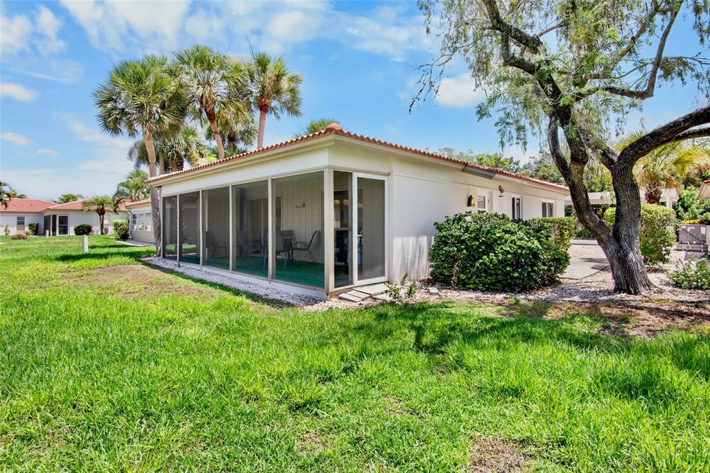 A single-story house features a screened-in porch, a tiled roof, and a large tree — 159 VISTA HERMOSA CIRCLE UNIT 27B, SARASOTA, FL