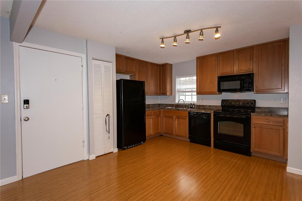 A kitchen features wood cabinets, black appliances, and light wood-look flooring — 317 E AMELIA STREET UNIT 8, ORLANDO, FL