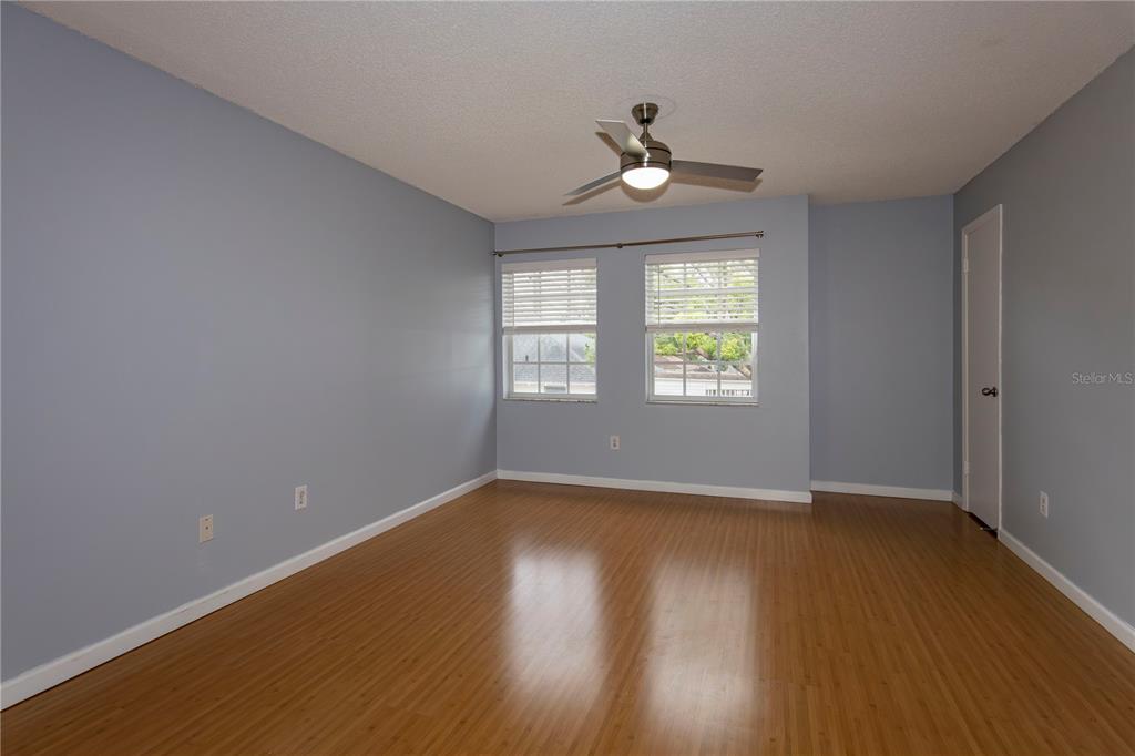 An empty bedroom features light blue walls, wood-look flooring, two windows, and a ceiling fan — 317 E AMELIA STREET UNIT 8, ORLANDO, FL