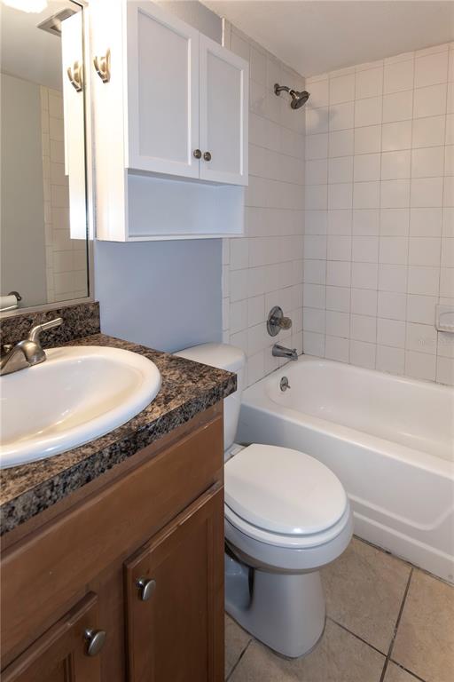 A bathroom features a vanity with a granite countertop, a toilet, and a tiled shower-tub — 317 E AMELIA STREET UNIT 8, ORLANDO, FL