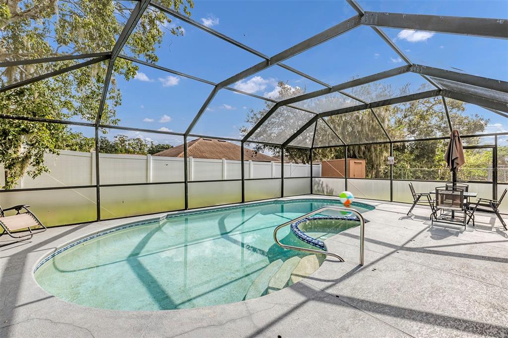 A screened-in swimming pool and spa area with a patio and white privacy fence — 819 NELSON DRIVE, KISSIMMEE, FL