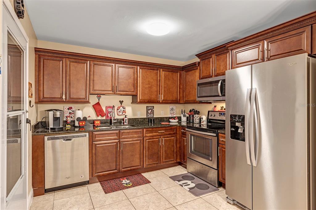 A kitchen featuring wood cabinets, stainless steel appliances, and tile flooring — 819 NELSON DRIVE, KISSIMMEE, FL