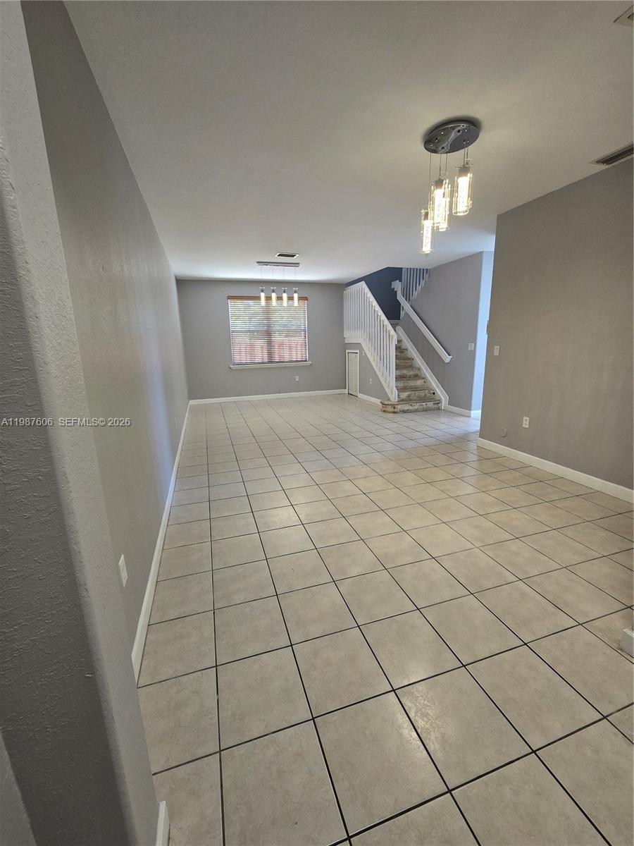 An open-concept living area features light-colored tile flooring, gray walls, and a staircase — 5630 NW 107th Ave # 1605, Doral FL 33178, DORAL, FL