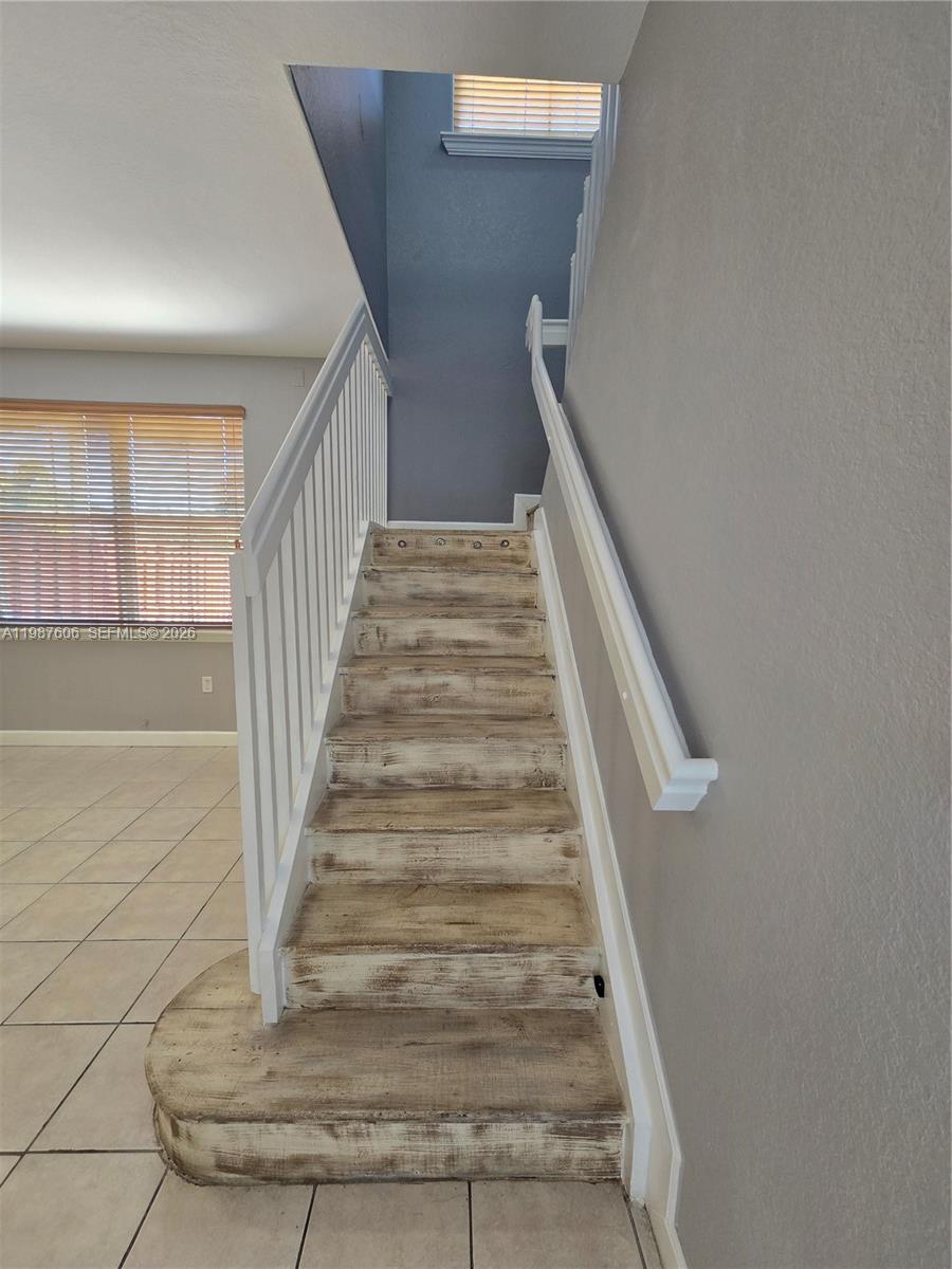 A staircase with distressed wood treads and white railings leads to an upper level — 5630 NW 107th Ave # 1605, Doral FL 33178, DORAL, FL