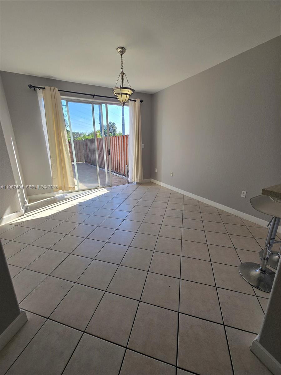 A dining area features tile flooring, a hanging light fixture, and sliding glass patio doors — 5630 NW 107th Ave # 1605, Doral FL 33178, DORAL, FL