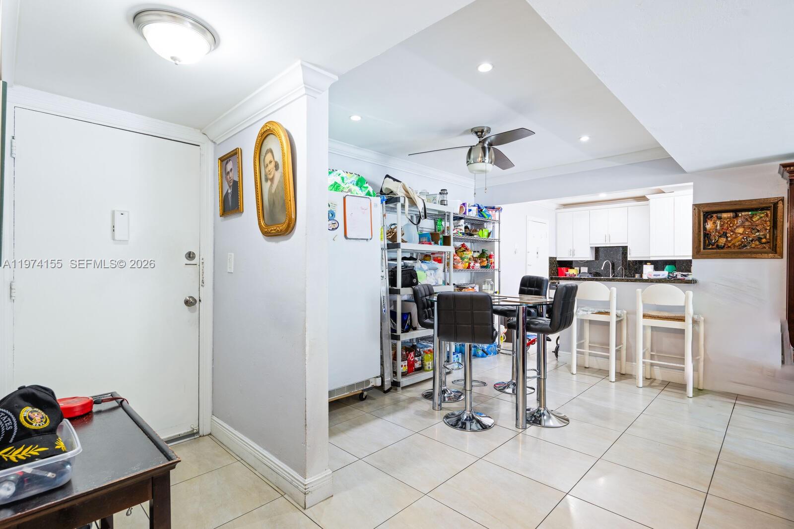 A dining area with a glass table, black stools, and metal shelving near a kitchen — 7401 SW 82nd st # 109s, Miami FL 33143, MIAMI, FL