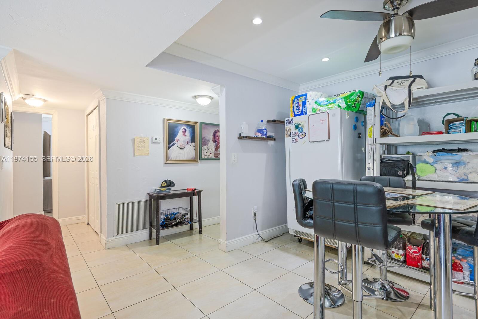 A dining area with a glass table, black chairs, and a refrigerator on tile flooring — 7401 SW 82nd st # 109s, Miami FL 33143, MIAMI, FL