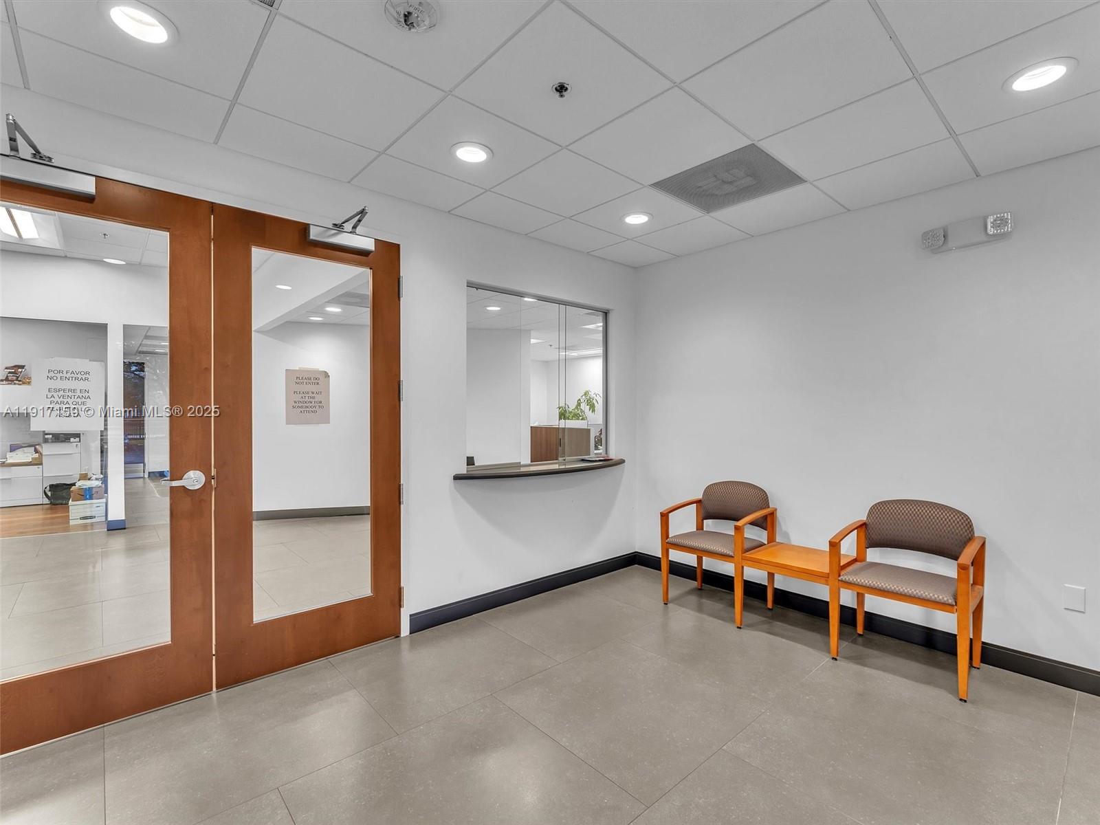 A waiting area features two chairs, a small table, and a glass service window — 10855 NW 27th St, Doral FL 33172, DORAL, FL