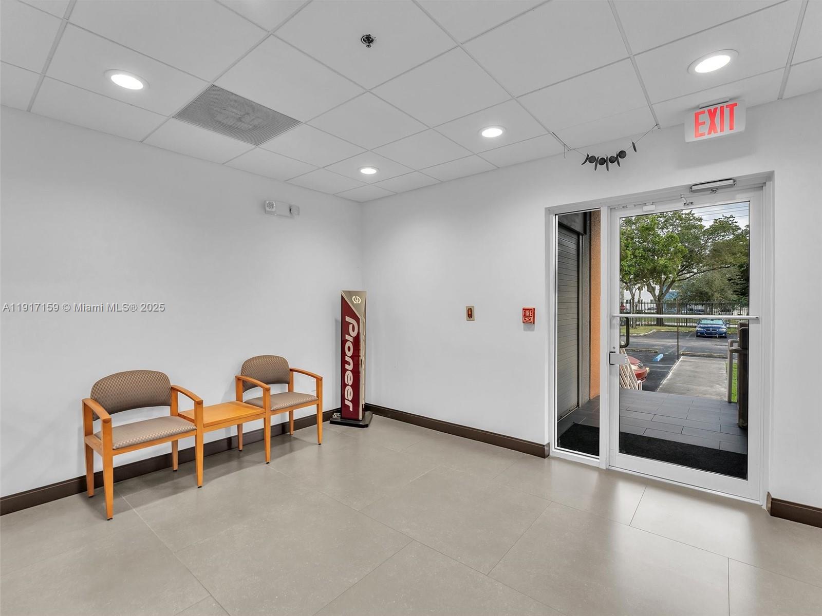 A waiting area features two chairs, a side table, a Pioneer sign, and a glass door — 10855 NW 27th St, Doral FL 33172, DORAL, FL