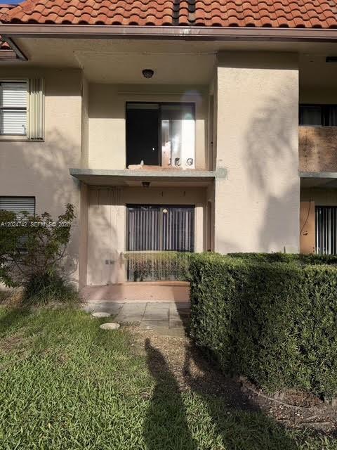 A two-story building exterior features a ground-level patio and an upper-level balcony with sliding doors — 15718 E Waterside Cir # 102, Sunrise FL 33326, SUNRISE, FL