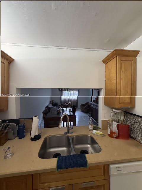 A kitchen sink with wooden cabinets overlooks a dining area through a wall opening — 15718 E Waterside Cir # 102, Sunrise FL 33326, SUNRISE, FL