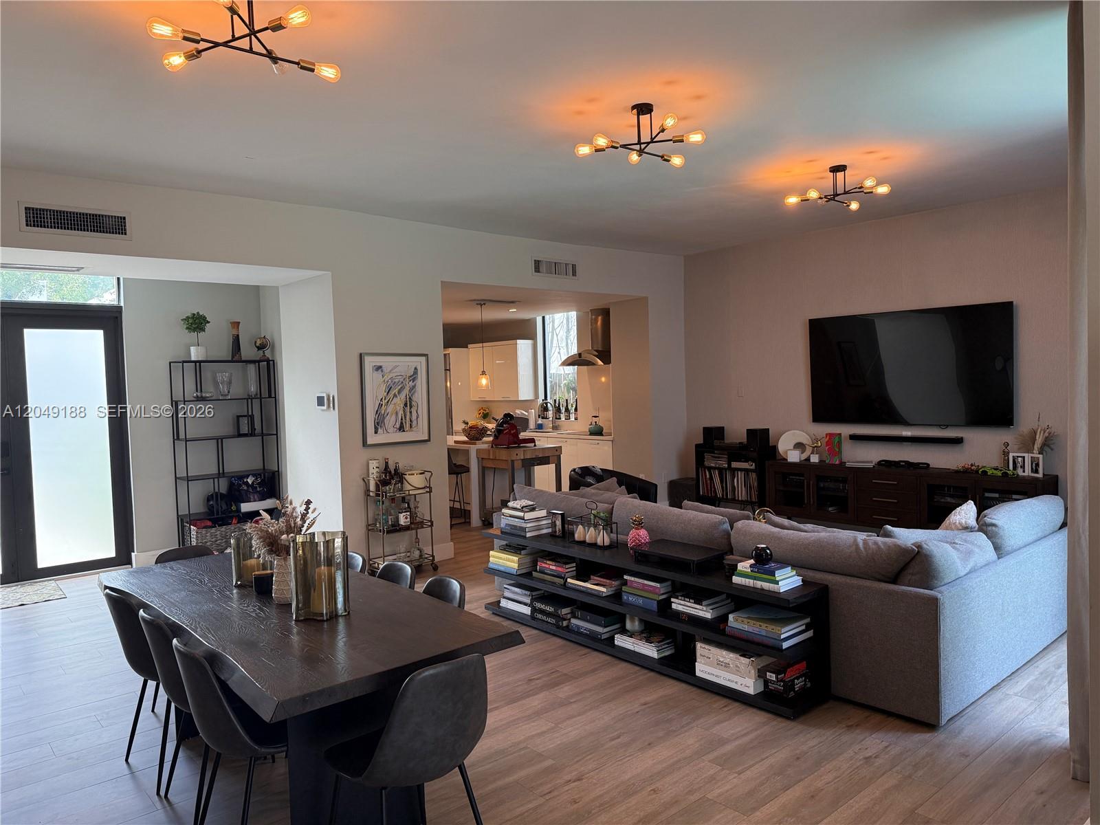 A modern open-concept living and dining area features wood-look flooring and floor-to-ceiling glass doors — 8631 Arboretum Ln, Miami FL 33138, MIAMI, FL