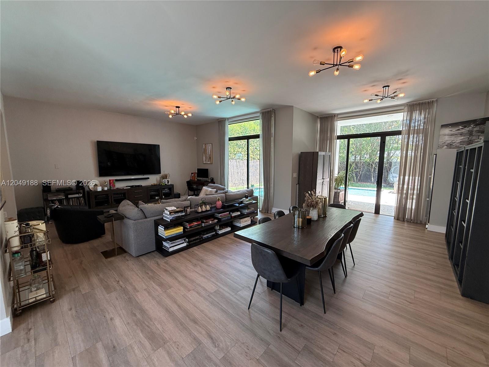 A dining room features a dark wood table, black chairs, and large bookshelves against the wall — 8631 Arboretum Ln, Miami FL 33138, MIAMI, FL