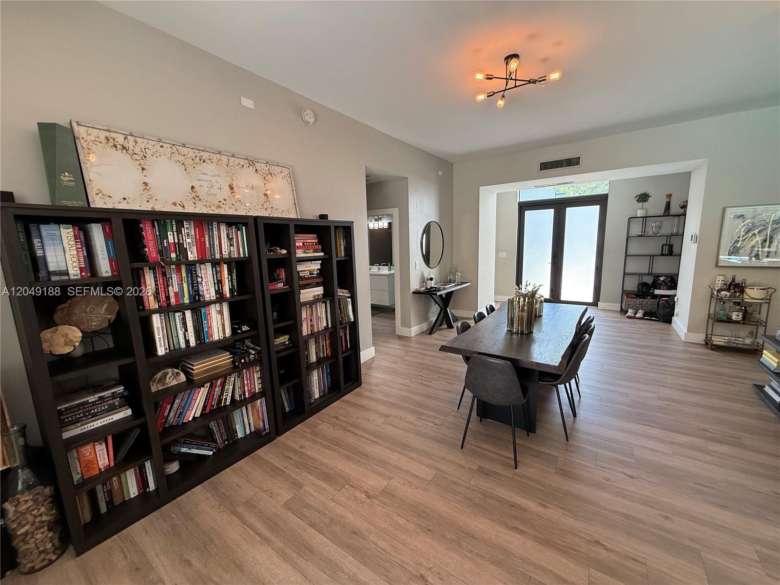 A spacious living room features a grey sectional sofa, wood flooring, and modern light fixtures — 8631 Arboretum Ln, Miami FL 33138, MIAMI, FL